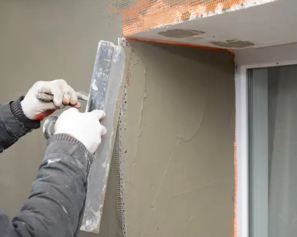 Lavori di intonacatura attorno alle finestre, con un cappotto che protegge le spallette. Si nota lo spessore dello strato di intonaco.