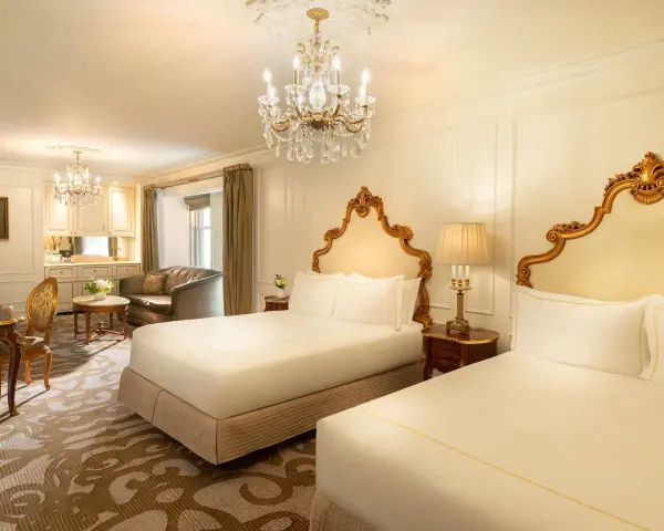 Luksusowy pokój z dwoma łóżkami w hotelu Plaza w Nowym Jorku, z kryształowym żyrandolem i złotymi zdobieniami. Zastanawiasz się, ile kosztuje noc w hotelu Plaza w Nowym Jorku?