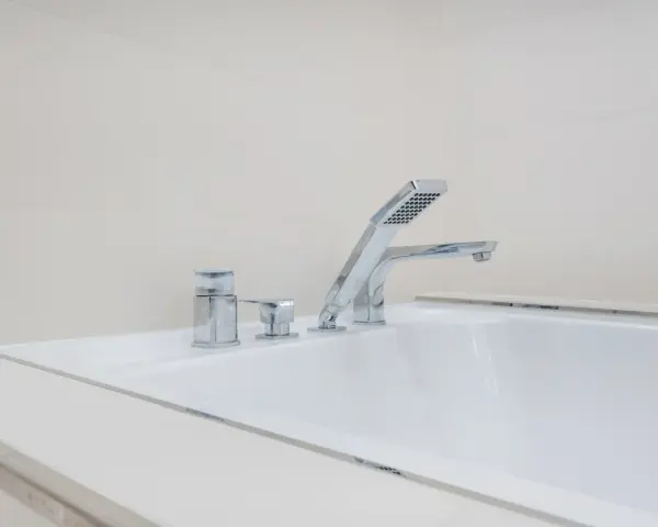 Elegancka bateria wannowa jednootworowa z chromowanymi elementami i słuchawką prysznicową, idealna do nowoczesnej łazienki.