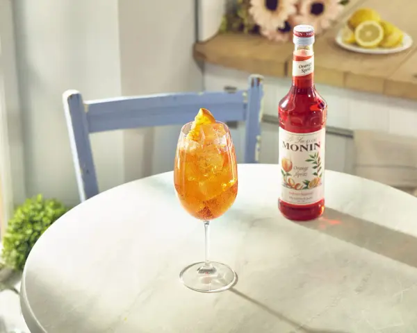 Orzeźwiający drink z syropem Monin Orange Spritz, lodem i pomarańczą. Idealny przepis na letnie popołudnie.
