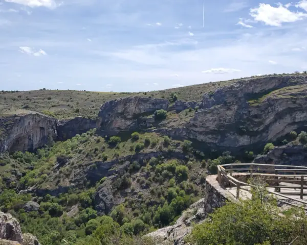 Impresionante vista del **barranco del Río Dulce**, con sus paredes rocosas, vegetación exuberante y un mirador de madera.