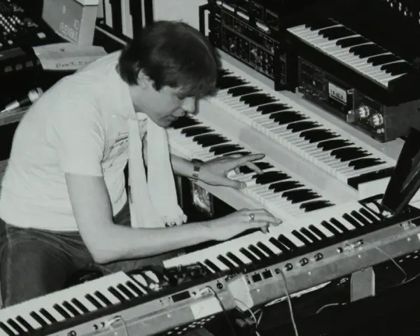 Mann spielt auf mehreren Synthesizern, die typische Klänge der 80er Jahre erzeugen.