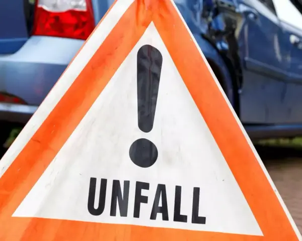 Warnschild "Unfall" vor beschädigtem Auto. Nach einem Verkehrsunfall kann eine Vorstandsbeschwerde bei der Versicherung nötig sein.