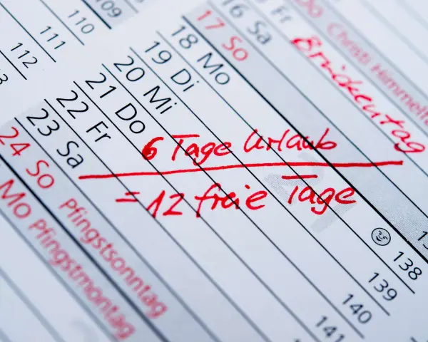 Kalenderblatt mit roten Markierungen: "6 Tage Urlaub = 12 freie Tage". Betriebsferien und Urlaubstage sind geplant.