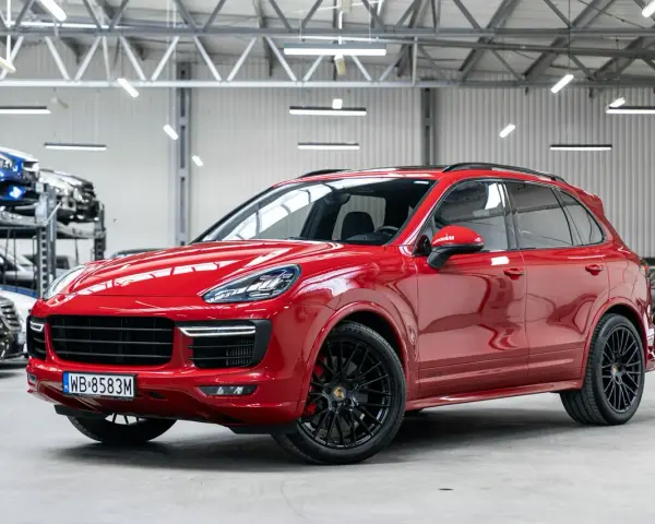 Czerwony Porsche Cayenne GTS lśni w salonie, gotowy na podbój dróg.