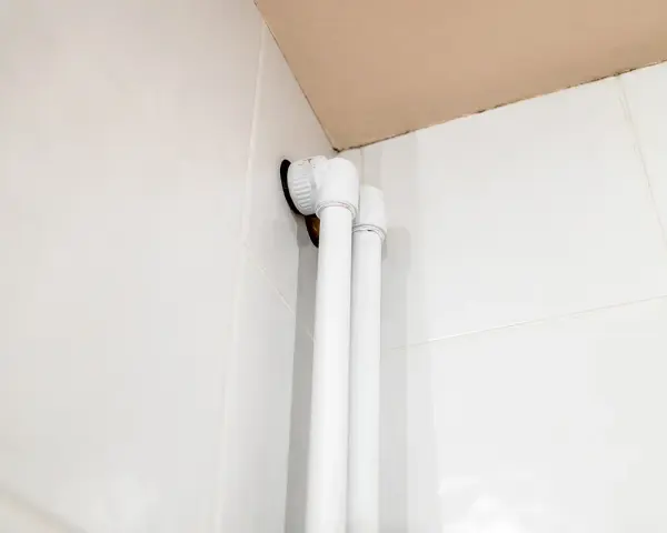 Białe osłonki na rury co, zamontowane przy białych kafelkach, tworzą estetyczne wykończenie instalacji.