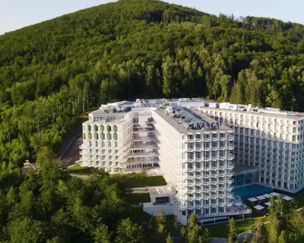 Nowy hotel w Wiśle, Crystal Mountain, wtopiony w zielone zbocze góry. Nowoczesna architektura z licznymi balkonami i basenem.