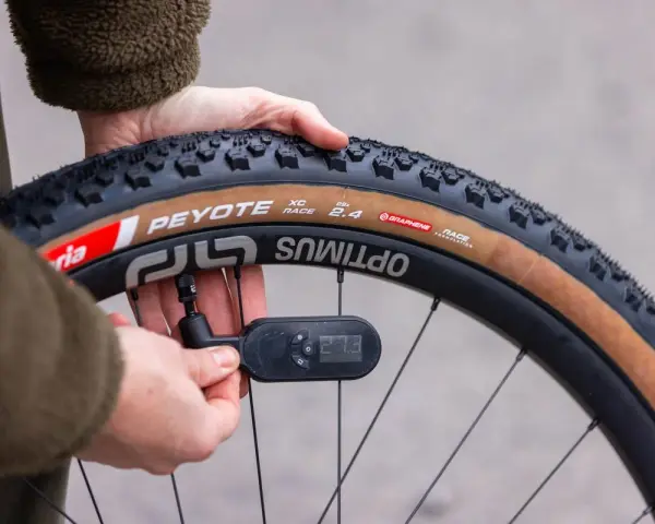 Checking the mountain bike tire pressure with a digital gauge. The tire reads 27.3 PSI.
