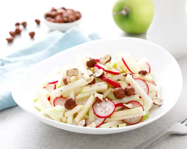 Frischer Kohlrabi Salat mit Radieschen und Haselnüssen, garniert mit Apfelstücken. Ein leichter Genuss!