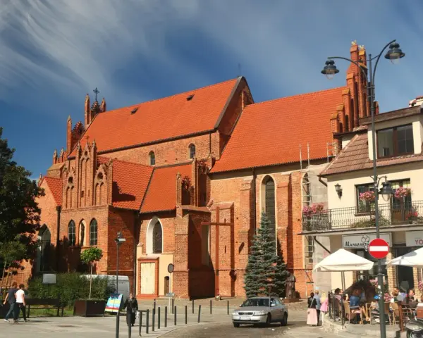 Gotycka ceglana bazylika w Tczewie, z pomarańczowym dachem, to jedna z głównych atrakcji miasta. W tle kawiarniany ogródek.