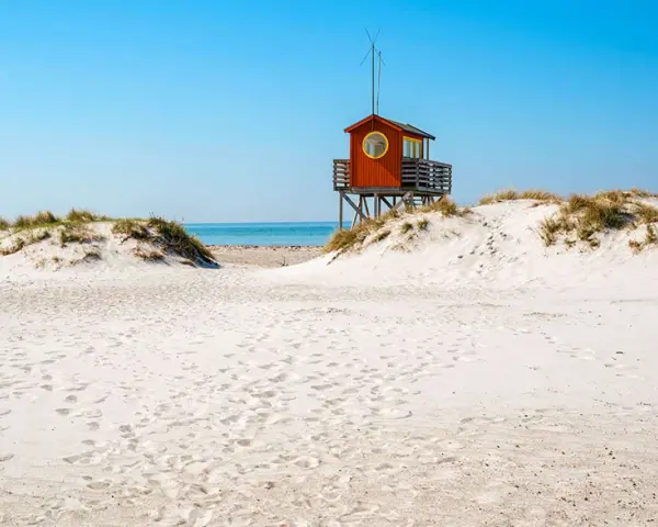 Piękne plaże w Szwecji z charakterystyczną czerwoną wieżą ratowniczą na wydmach.