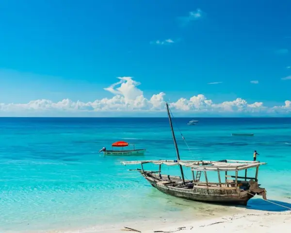 Piękna plaża na Zanzibarze, turkusowa woda, łodzie i marzenia o wakacjach. Może nawet o zarobieniu tam zanzibar dolary.
