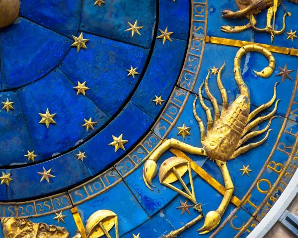 Złoty skorpion, symbol zodiaku, na niebieskiej tarczy z gwiazdami i cyframi.