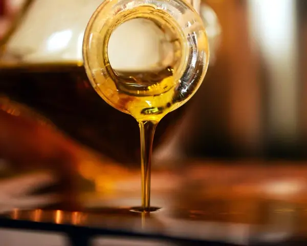 Olio d'oliva dorato cola da una bottiglia. Scopri come conservare l'olio di oliva per mantenerne intatto il sapore.
