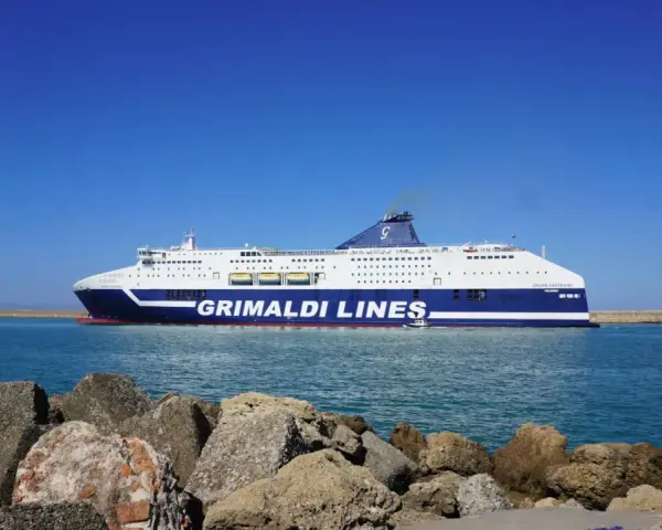 Prom Grimaldi Lines wypływa z Livorno do Palermo. Statek "Cruise Sardegna" na tle błękitnego nieba i morza.