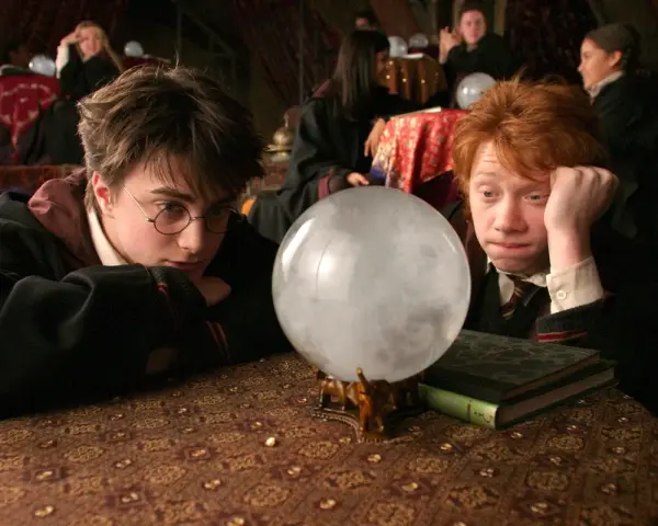 Harry i Ron wpatrują się w wirującą mgłę kryształowej kuli, która mówi, szukając odpowiedzi na lekcji wróżbiarstwa.