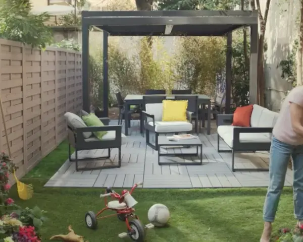 Donna annaffia fiori in un giardino con mobili moderni e un triciclo, un esempio di giardino idee originali.