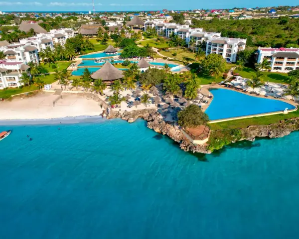 Widok z samolotu na tropikalny kurort na Zanzibarze z białymi budynkami, basenami i plażą nad turkusowym oceanem.