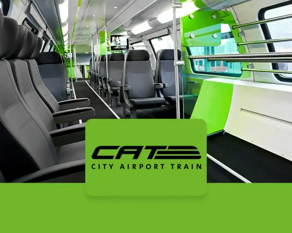 Wnętrze nowoczesnego pociągu CAT, czyli City Airport Train w Wiedniu. Jasne siedzenia i zielone akcenty tworzą przestronną atmosferę.