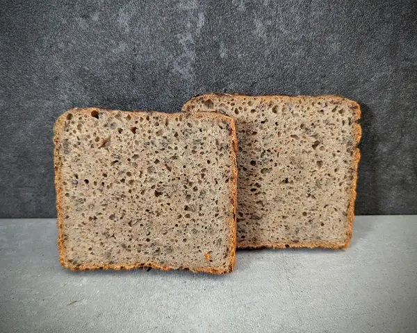 Zwei Scheiben rustikales Vollkornbrot, perfekt für Brot backen ohne Form. Die Kruste ist knusprig, die Krume luftig und voller Körner.
