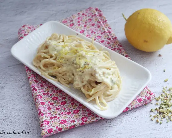 Spaghetti al limone cremosi, un piatto invitante con scorza di limone grattugiata e pistacchi tritati.