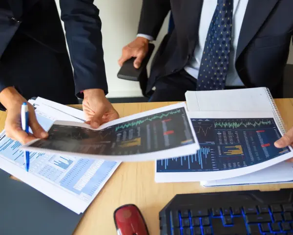 Dos personas analizan gráficos financieros, discutiendo los diferentes tipos de auditorías y sus implicaciones para el negocio.