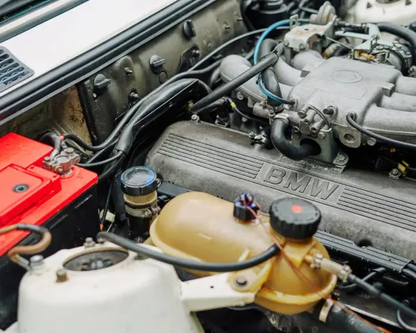 Silnik BMW 1.6 mpi z widocznym akumulatorem i zbiorniczkiem płynu.
