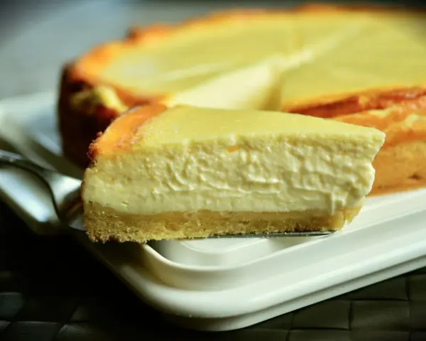 Una rebanada cremosa de tarta de queso Philadelphia, con su base dorada y relleno suave, lista para ser disfrutada.