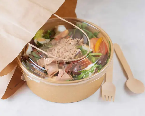 Ensalada de atún para llevar, con ingredientes frescos y cubiertos en un recipiente ecológico. Perfecta para tu licencia take away.