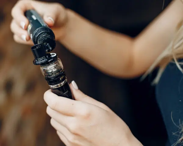 Manos rellenando un cigarrillo electrónico. El líquido de nicotina es mucho, ¡cuidado!
