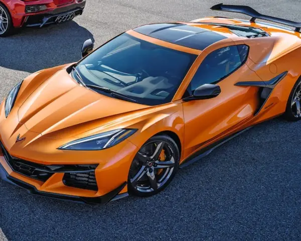 Pomarańczowy Chevrolet Corvette C8 z czarnym dachem i spojlerem na torze wyścigowym. Obok widać fragment czerwonego samochodu.