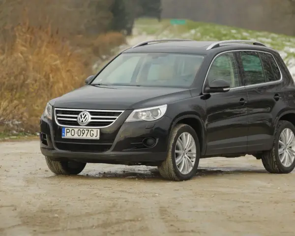 Czarny Volkswagen Tiguan, jeden z najmniej awaryjnych SUV-ów 10 letnich, na drodze gruntowej.