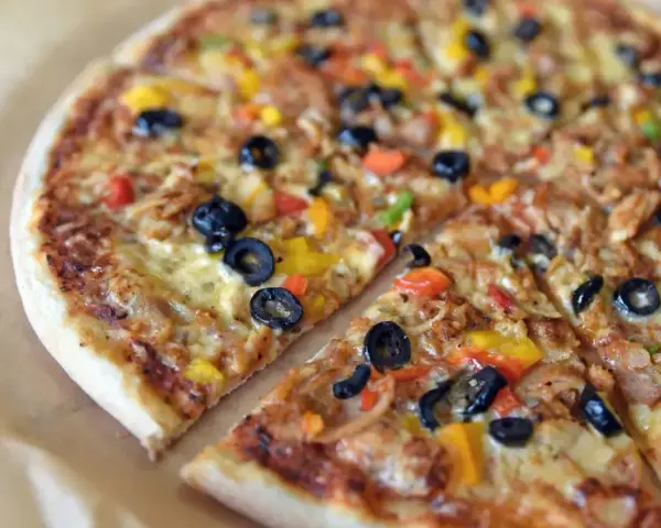 Pyszna pizza z kurczakiem, oliwkami i kolorową papryką. Różne rodzaje pizzy mogą zawierać podobne składniki, ale ta wygląda wyjątkowo apetycznie.