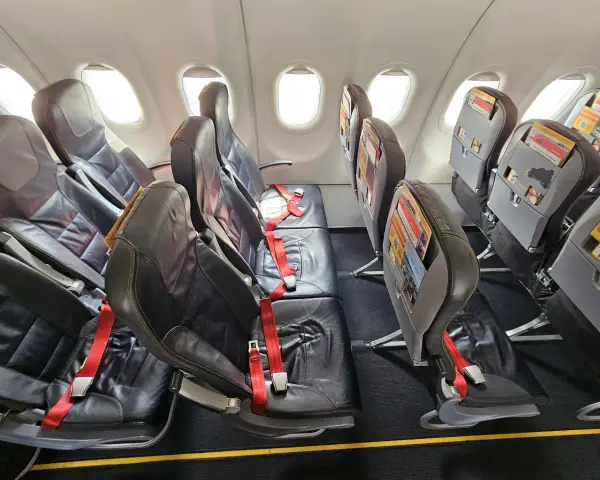 Puste fotele w samolocie, czerwone pasy bezpieczeństwa. Czy warto lecieć Pegasus Airlines? Opinie pasażerów są różne.