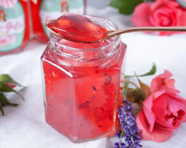 Ein Glas Sylter Rosenmarmelade, verziert mit Rosen und Lavendel. Ein köstliches Rezept für den Sommer.