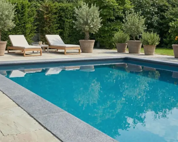 Luxuriöser Pool mit Steinumrandung und mediterranen Pflanzen. Tolle pool verkleiden ideen für eine elegante Poollandschaft.