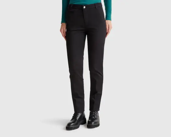 Mujer con pantalones chinos negros y botines gruesos. Un look moderno y versátil.
