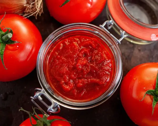 Frische Tomaten um ein Glas mit selbstgemachtem Tomatenmark. Perfekt für Saucen und mehr!