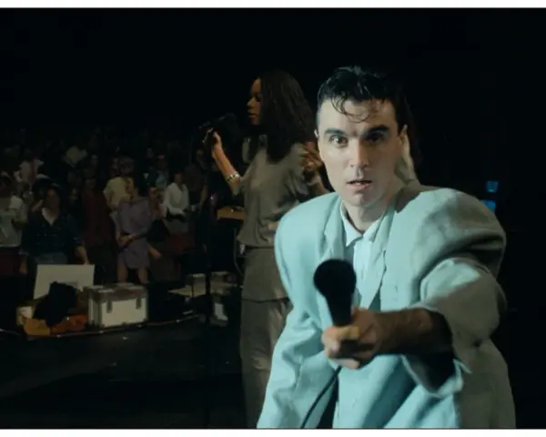 David Byrne z The Cult - Be Free, śpiewa do mikrofonu na tle tłumu.