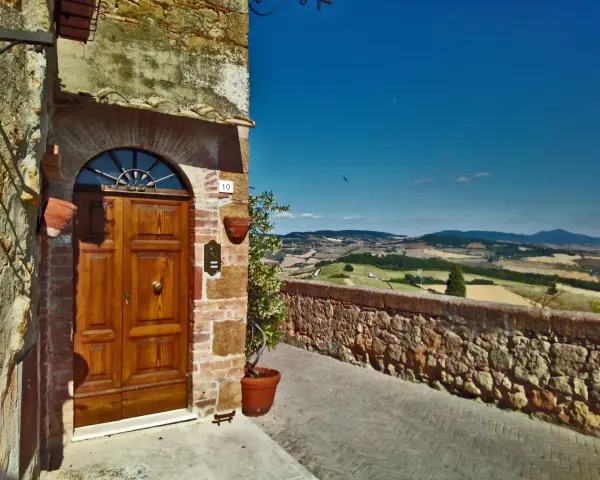 Un portone in legno in un borgo toscano, con vista panoramica sulle colline. Perfetto per un tour in moto tra i borghi più belli della Toscana.