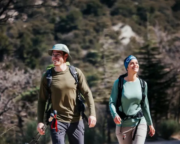 Randonneurs souriants malgré la chaleur, le mal de tête guette peut-être. Ils marchent sur un sentier rocailleux.