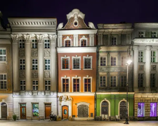 Nocny widok na kolorowe kamienice Starego Rynku w Poznaniu, przypominające urokliwe osiedle warszawskie.