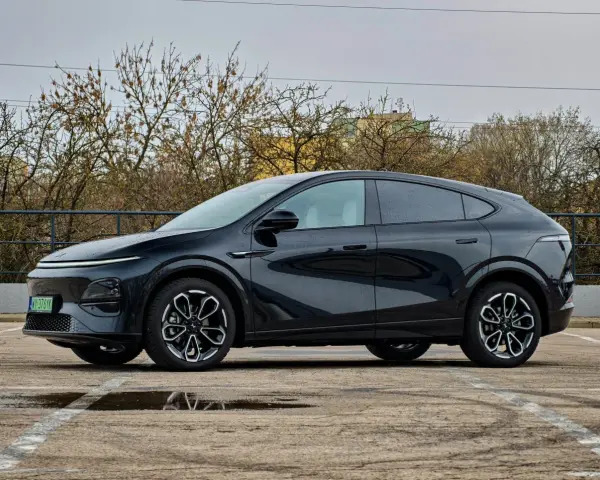 Elegancki, czarny Xpeng G6 stoi na parkingu, odbijając się w kałużach.