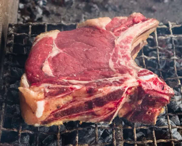 Bistecca alla fiorentina cruda su griglia, pronta per la cottura. Il tempo cottura fiorentina è fondamentale per una perfetta riuscita.