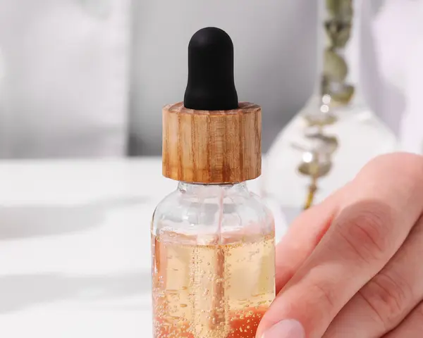 Dłoń trzymająca serum z pipetką. Składniki takie jak EDTA w kosmetykach pomagają stabilizować formuły.