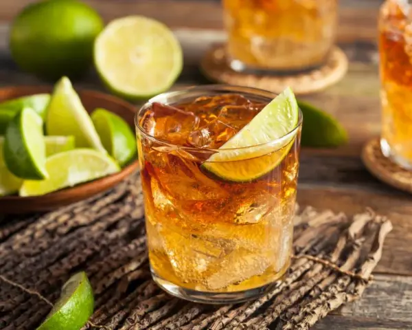 Idealny drink z rumem i lodem, ozdobiony plasterkiem limonki. Obok miseczka z kawałkami limonki, sugerująca, z czym pić rum.