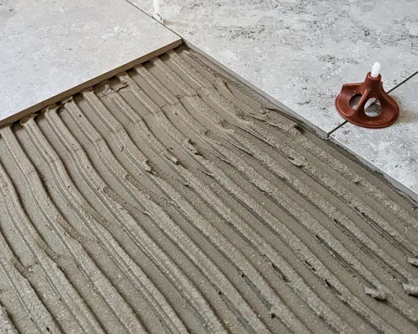 Läggning av klinker på betonggolv med fix. En del av golvet är täckt med fix, redo för nästa platta.