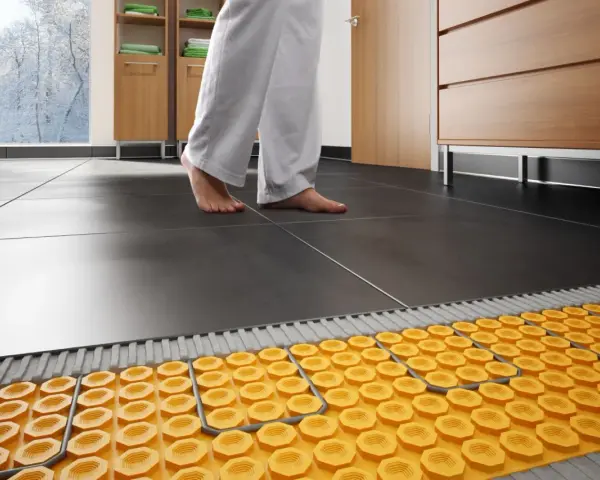 Piedi nudi su un pavimento piastrellato, con un sistema di riscaldamento ad aria calda visibile sotto.