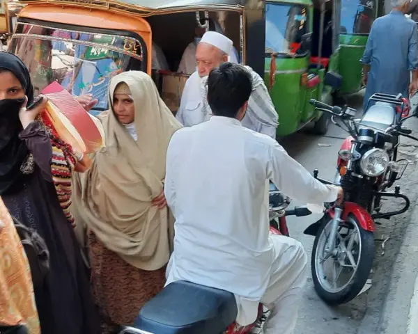 Ludzie na ulicy w Pakistanie, wśród nich kobiety w hidżabach i dzieci. Czy pakistan jest bezpieczny? Tłum na targu, ruchliwa ulica.