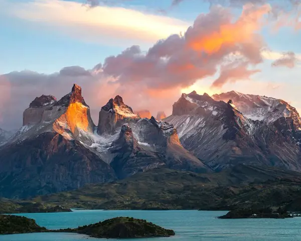Wspaniała wycieczka do Chile! Słońce oświetla skaliste szczyty Torres del Paine, odbijając się w turkusowym jeziorze.